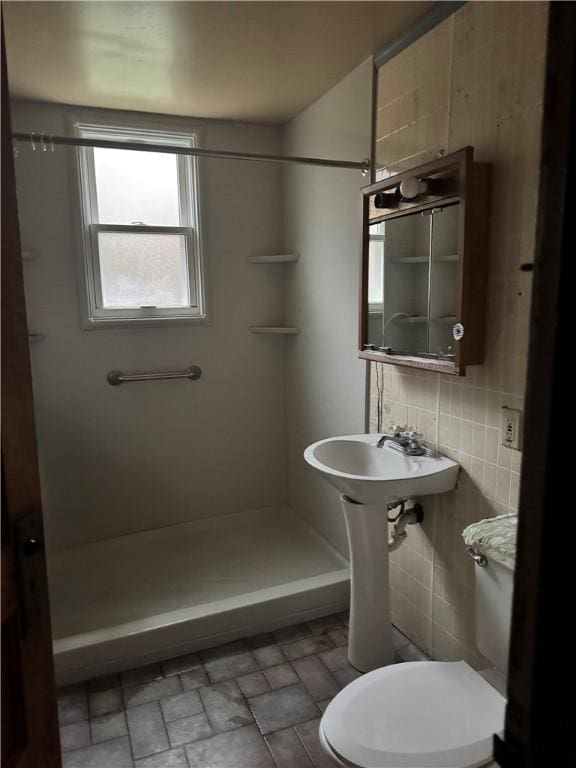 bathroom with tasteful backsplash, walk in shower, sink, tile walls, and toilet