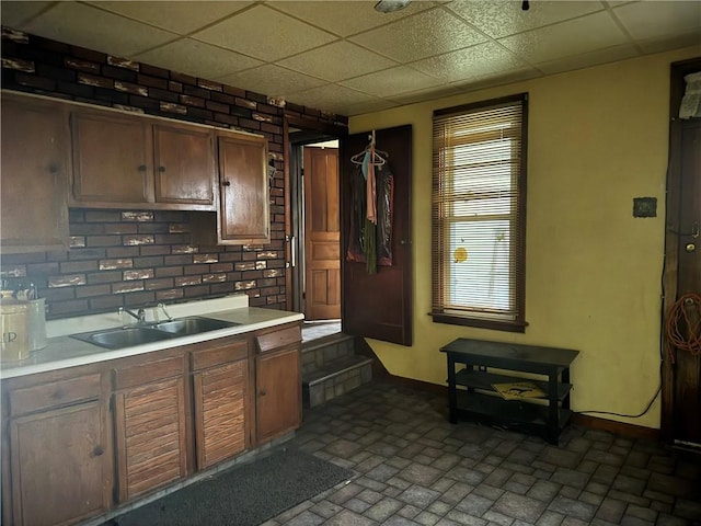 kitchen featuring decorative backsplash, sink, and a drop ceiling