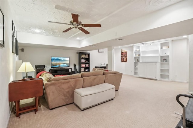 carpeted living room featuring a tray ceiling, ceiling fan, and a textured ceiling