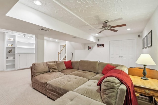 living room with light carpet, ceiling fan, and a textured ceiling