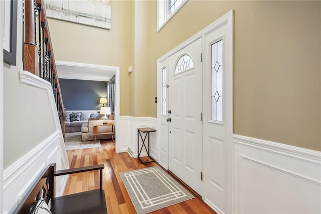 entryway featuring a towering ceiling and light hardwood / wood-style flooring