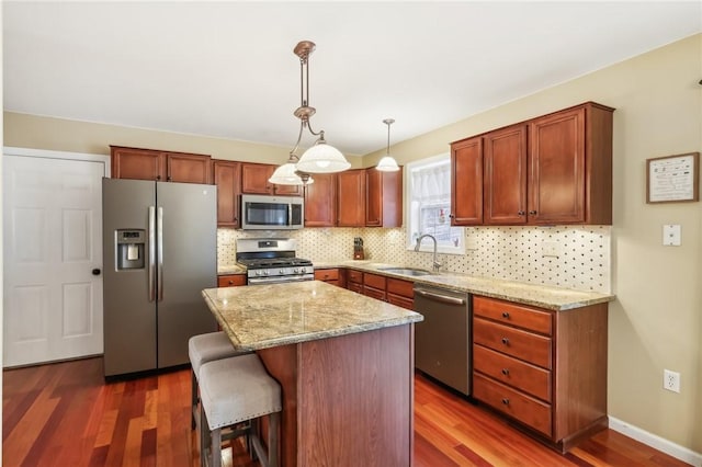 kitchen featuring a center island, dark wood-type flooring, sink, hanging light fixtures, and stainless steel appliances