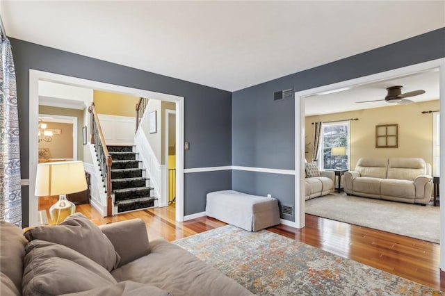 living room with ceiling fan with notable chandelier and light wood-type flooring