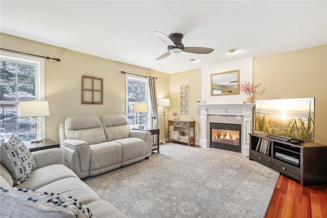 living room with hardwood / wood-style floors, ceiling fan, and a tiled fireplace