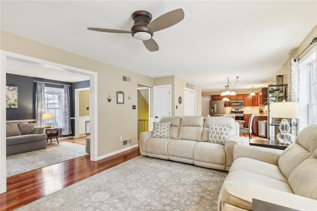 living room featuring wood-type flooring and ceiling fan with notable chandelier