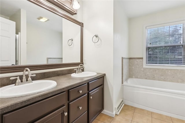 bathroom featuring tile patterned floors, vanity, baseboard heating, and a tub to relax in