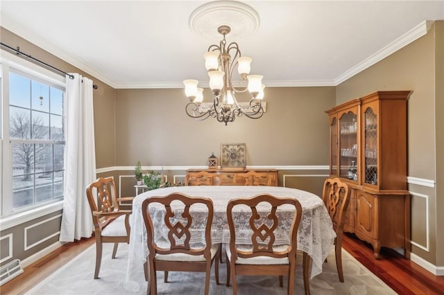 dining area featuring hardwood / wood-style floors, ornamental molding, and an inviting chandelier