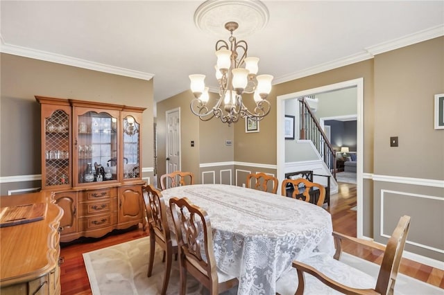 dining space with dark hardwood / wood-style floors, ornamental molding, and a chandelier