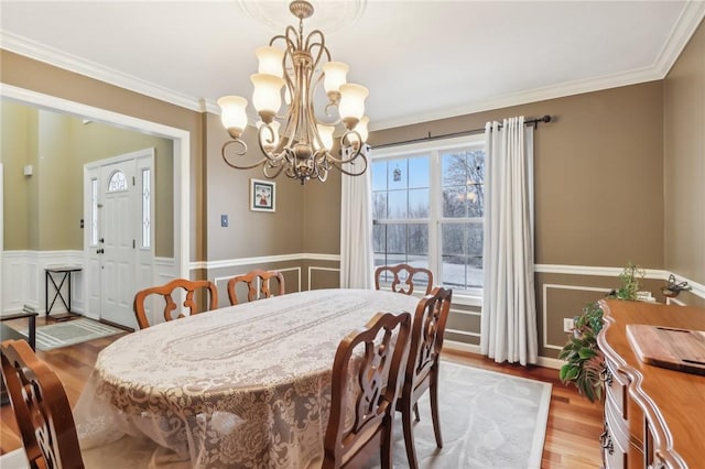 dining space with hardwood / wood-style flooring, crown molding, and an inviting chandelier