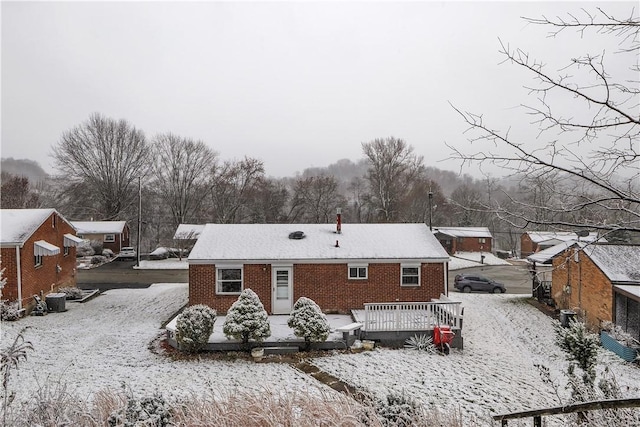 snow covered back of property with central AC unit and a deck