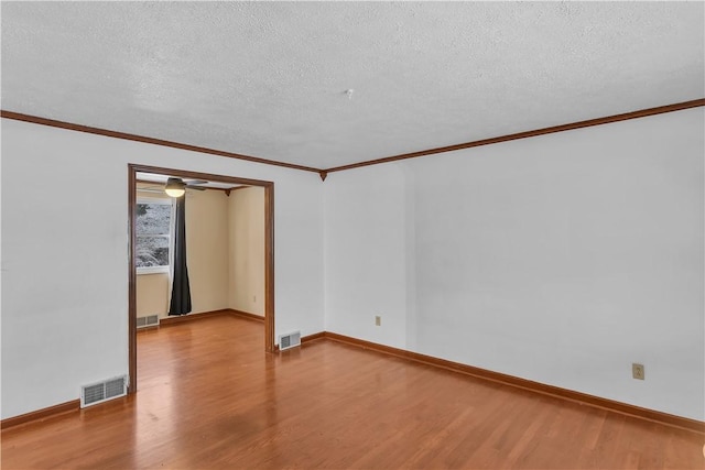 empty room with wood-type flooring, a textured ceiling, and ornamental molding