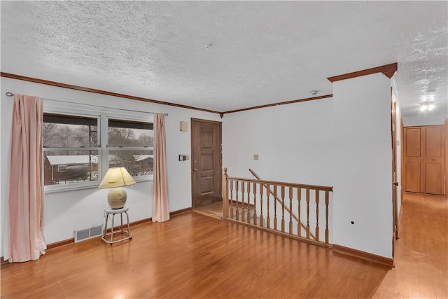 unfurnished room with wood-type flooring, a textured ceiling, and ornamental molding