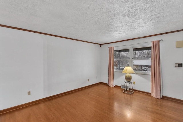 empty room featuring wood-type flooring, a textured ceiling, and ornamental molding