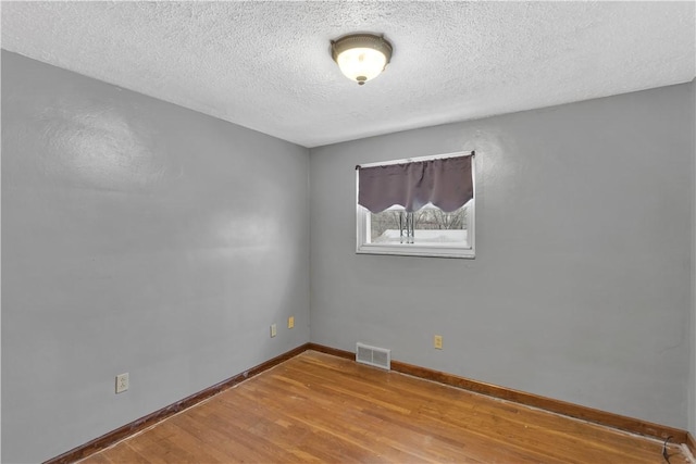 spare room featuring light hardwood / wood-style flooring and a textured ceiling