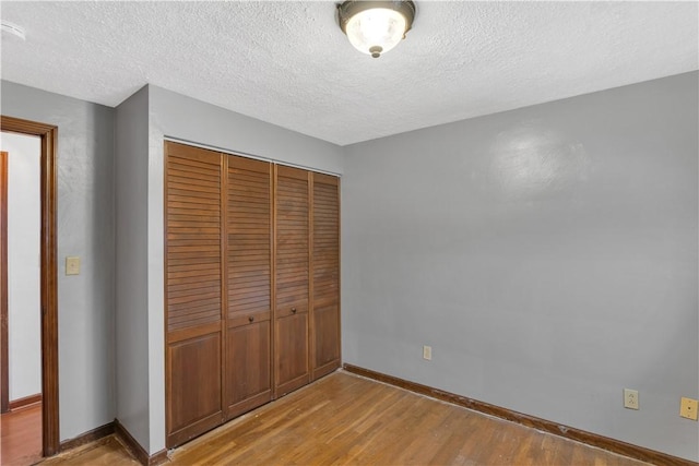 unfurnished bedroom with a textured ceiling, light hardwood / wood-style flooring, and a closet