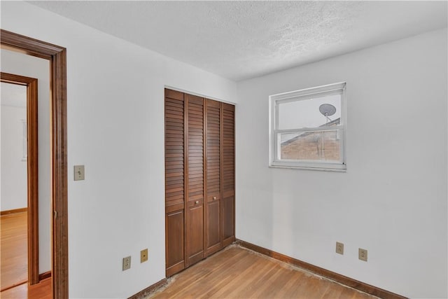 unfurnished bedroom featuring a closet, light hardwood / wood-style flooring, and a textured ceiling