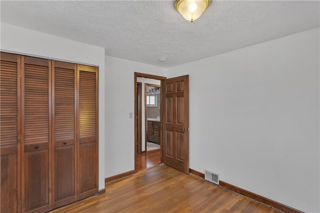 unfurnished bedroom featuring wood-type flooring, a textured ceiling, and a closet