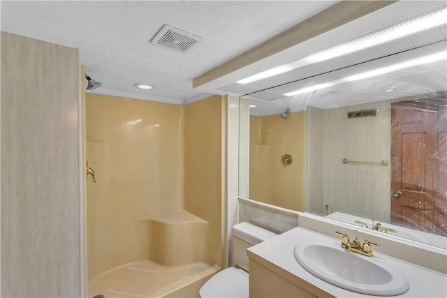 bathroom with a textured ceiling, vanity, toilet, and walk in shower