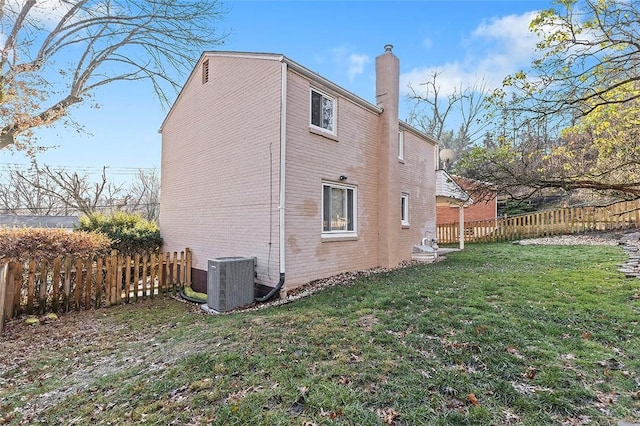 view of side of home featuring a fenced backyard, cooling unit, a chimney, and a lawn