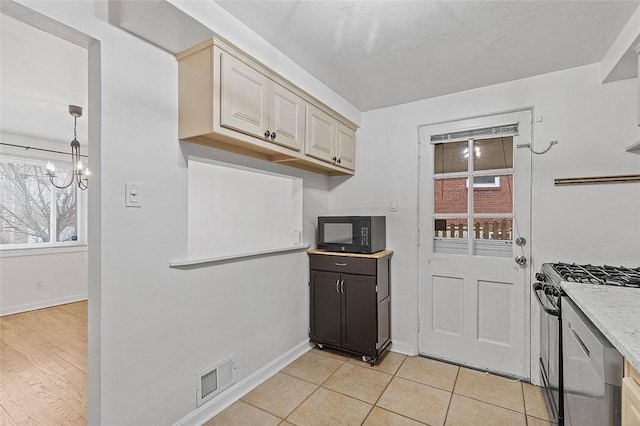 kitchen featuring range with gas stovetop, decorative light fixtures, light tile patterned floors, an inviting chandelier, and cream cabinetry