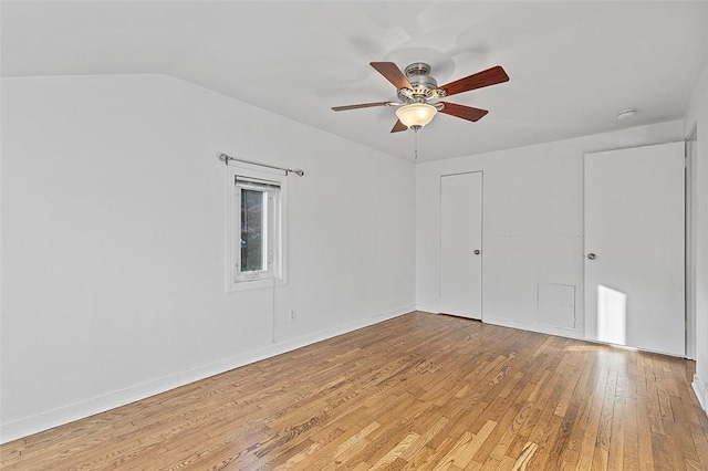 spare room featuring ceiling fan, light wood finished floors, vaulted ceiling, and baseboards
