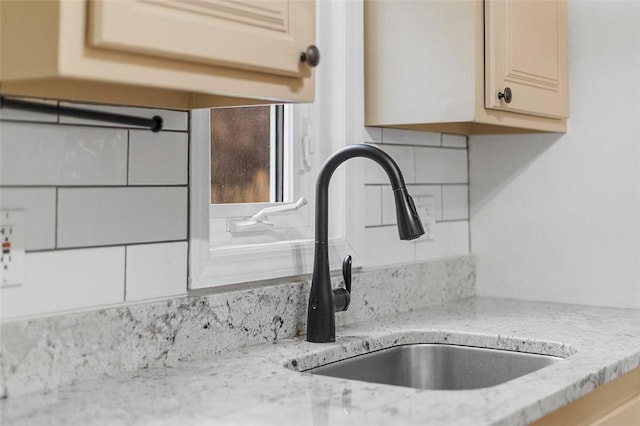 details with sink, decorative backsplash, and light stone countertops