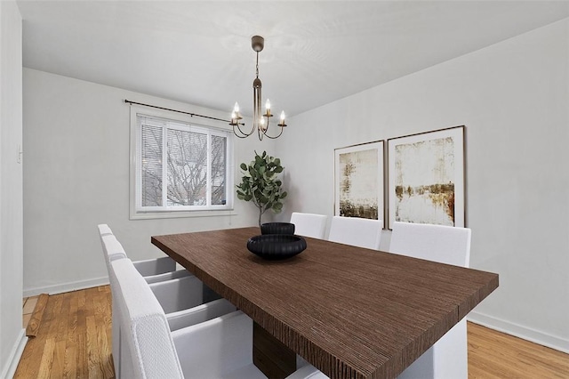dining area with baseboards, light wood-type flooring, and a chandelier
