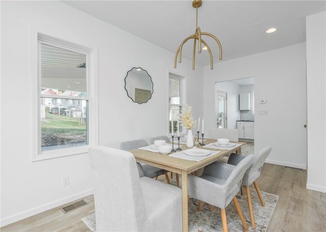 dining room with a notable chandelier, a healthy amount of sunlight, and light hardwood / wood-style floors