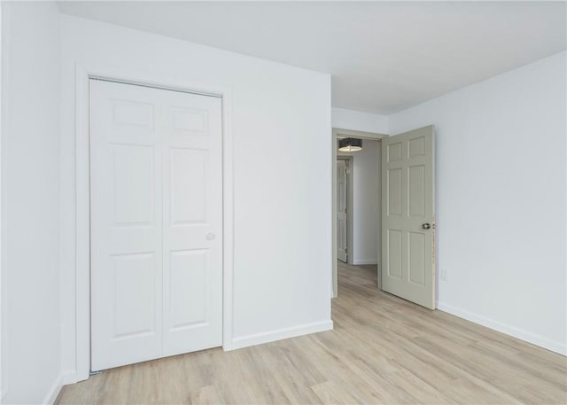 unfurnished bedroom with light wood-type flooring and a closet