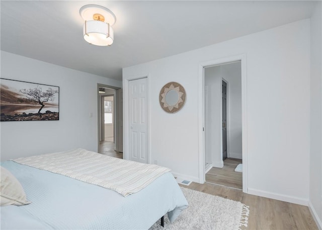 bedroom with light hardwood / wood-style floors, connected bathroom, and a closet