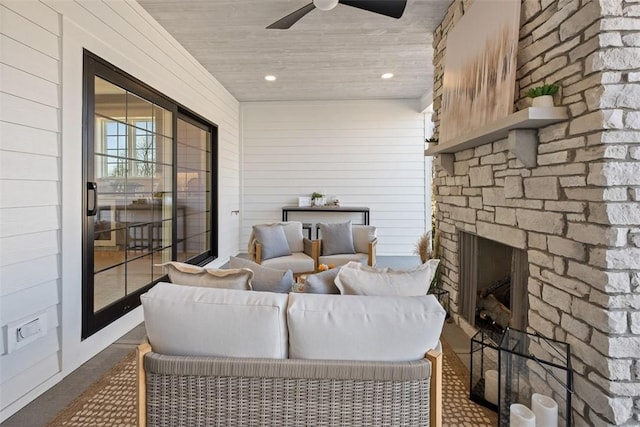 living room featuring an outdoor stone fireplace and ceiling fan