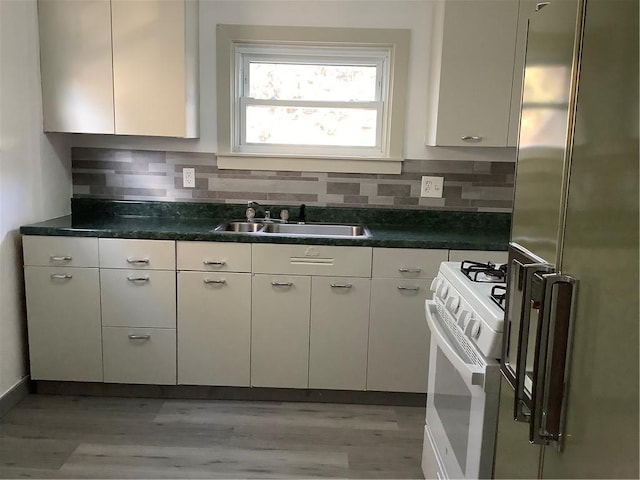 kitchen with white electric range, sink, stainless steel fridge, light wood-type flooring, and tasteful backsplash