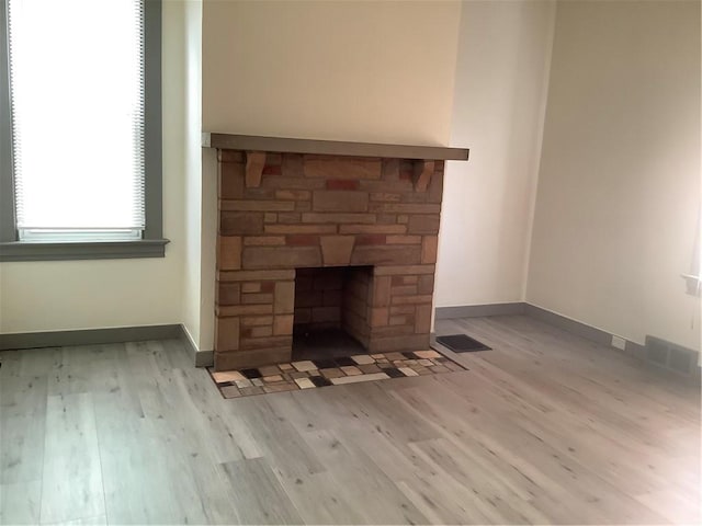 details with a stone fireplace and wood-type flooring