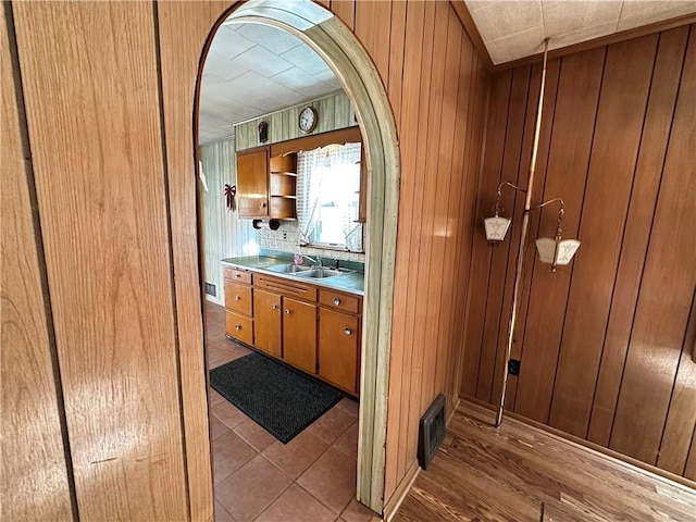 bar featuring tasteful backsplash, wooden walls, light hardwood / wood-style flooring, and sink