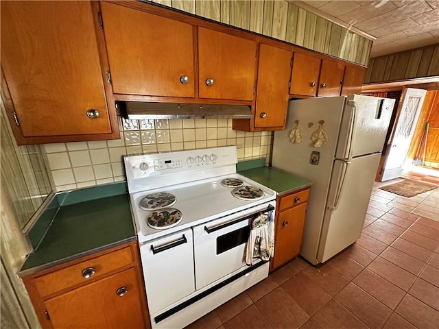 kitchen with dark tile patterned flooring, white appliances, and tasteful backsplash