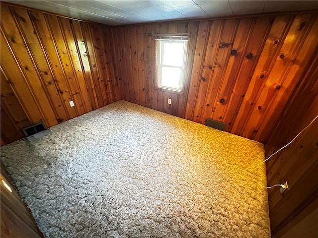 carpeted spare room featuring wooden walls