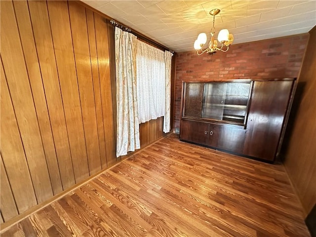 unfurnished dining area featuring a chandelier, wood-type flooring, and wood walls