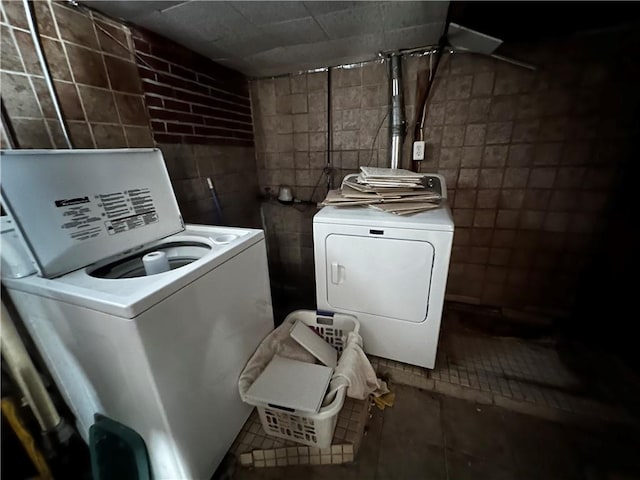 laundry area featuring tile patterned floors, washing machine and clothes dryer, and tile walls