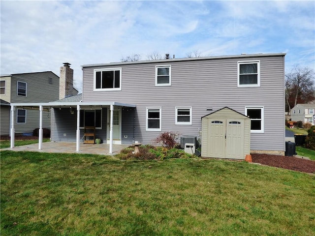 back of property with a lawn, central AC, a patio, and a storage shed