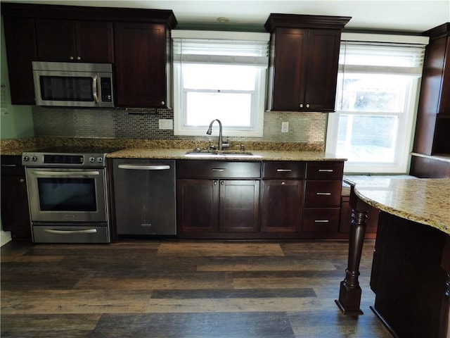 kitchen featuring dark wood-type flooring, sink, decorative backsplash, light stone countertops, and appliances with stainless steel finishes