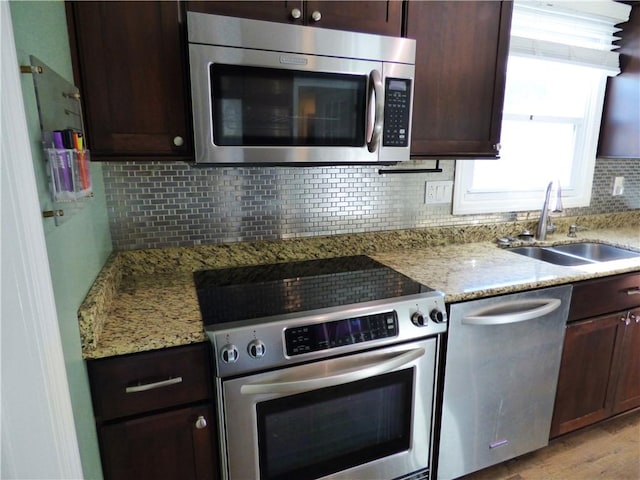 kitchen with light stone counters, sink, light hardwood / wood-style flooring, and appliances with stainless steel finishes