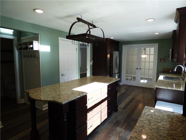 kitchen with french doors, light stone counters, sink, a center island, and dark hardwood / wood-style floors