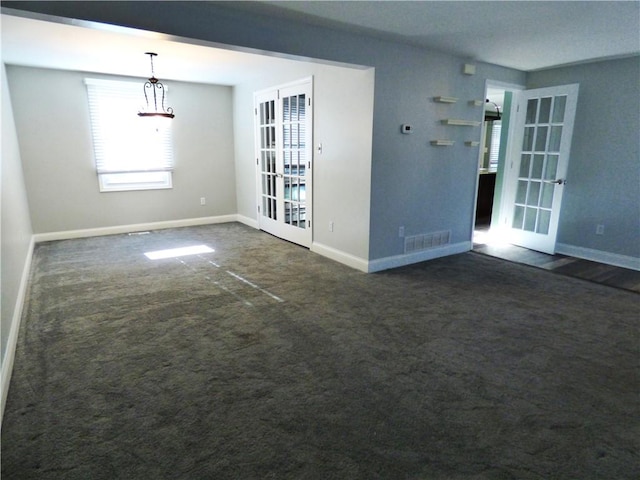 spare room featuring dark colored carpet and french doors