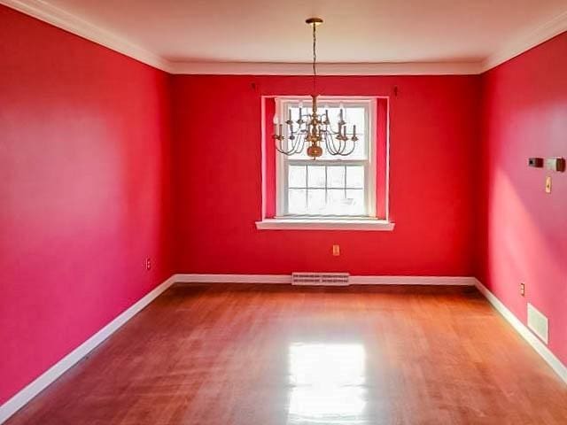 unfurnished dining area with hardwood / wood-style floors, an inviting chandelier, and ornamental molding