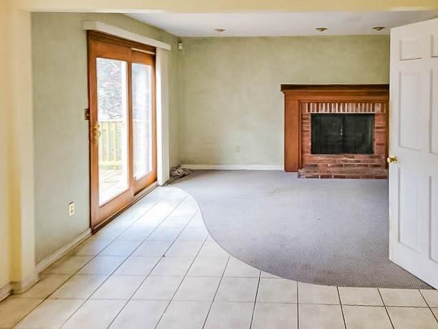 unfurnished living room featuring light tile patterned floors, a brick fireplace, and a healthy amount of sunlight