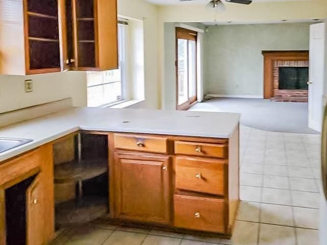 kitchen with ceiling fan, light tile patterned flooring, and a brick fireplace