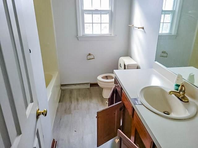 bathroom featuring vanity, toilet, wood-type flooring, and a washtub