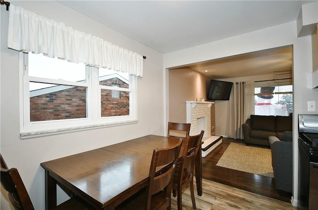 dining room with a brick fireplace and hardwood / wood-style flooring