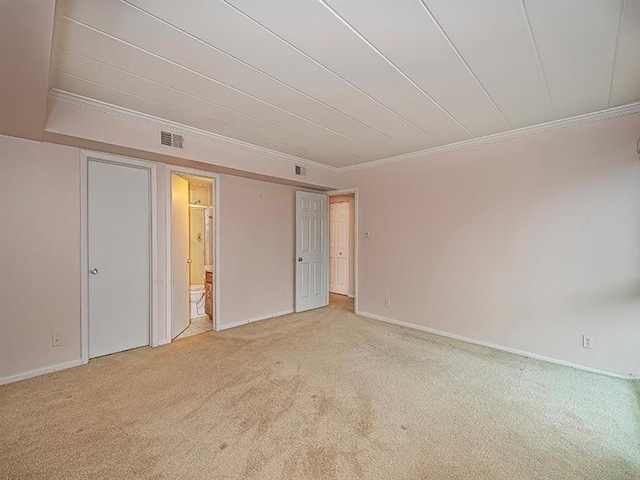 unfurnished bedroom with light colored carpet, crown molding, and ensuite bath