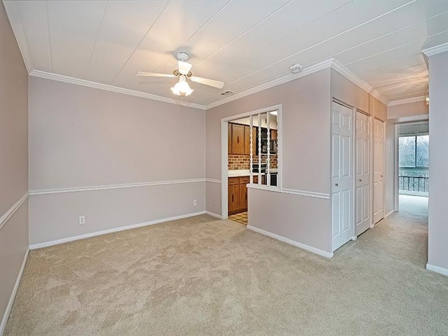 carpeted spare room with ceiling fan and ornamental molding